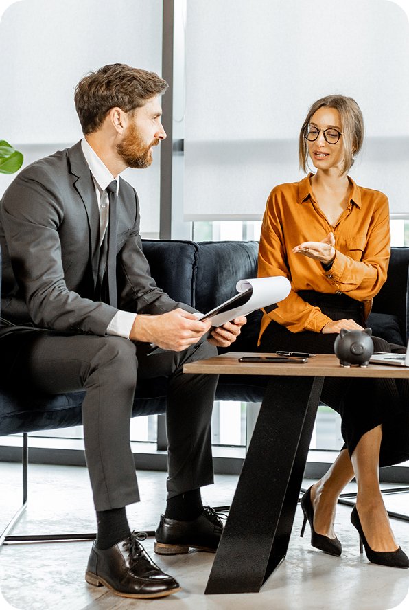 Two business professionals sitting and discussing documents in a modern office.